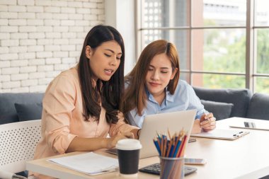 İki iş kadını takım toplantısı şirket masasında dizüstü bilgisayarla yapılıyor. Finansal grafik grafikleri okuyan iki genç kadın pazarlama verilerini analiz etmeyi planlıyor. Asyalı ekip çalışma bürosu.