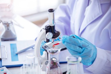 Tıp laboratuarındaki kadın bilim adamı el yazısı bilgileri mikroskop tıbbi testleri, biyoloji kimyasını inceler. Asya kadın teknisyen laboratuarı kan testi farmasötik analizi yapıyor.