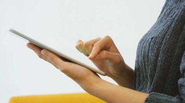 İnternetten dijital tablet alışverişi yapan Asyalı bir kadın arıyor, mesaj yolluyor, internet teknolojisi yaşam tarzında gülümsüyor. Asyalı kadın akıllı tablete dokunuyor mobil uygulama ev ofisini kullanarak ellere odaklanıyor.