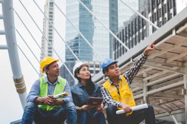 İnşaat mühendisi takımları modern kentteki inşaat sahasında birlikte çalışan işçi kaskı takıyorlar. Foreman Endüstri Mühendislik Mühendisliği ekip çalışması. Asya endüstrisi profesyonel takımı