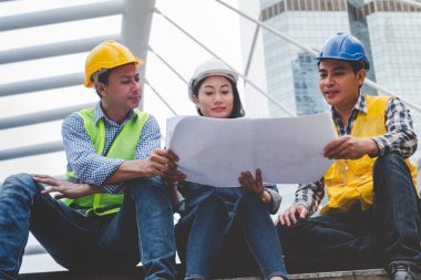 İnşaat mühendisi takımları modern kentteki inşaat sahasında birlikte çalışan işçi kaskı takıyorlar. Foreman Endüstri Mühendislik Mühendisliği ekip çalışması. Asya endüstrisi profesyonel takımı