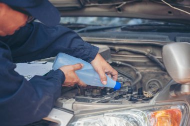 Araba tamircisi elleri araba aküsü mekanik servisi için arıtılmış arıtılmış su döküyor. Kapatın elleri adamım. Deiyonize edilmiş sıvı su şişesini garajdaki mobil araba servisinde tutun.