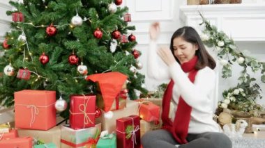 Noel ağacının altında hediye paketi yapan bir kadın. Asyalı kadın dekorasyon balosu balosu Noel ağacı, Noel bayramı kış mevsimsel kutlaması. Hediye paketini sıcak oturma odasına sarın.