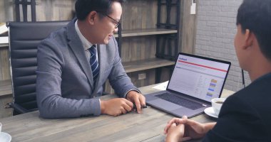 Mutluluk iki iş adamı ofis masasında kendine güvenen ekip toplantısı yapıyor. Dizüstü bilgisayarla çalışan iş ortakları. Asyalı adam iş arkadaşlığı toplantısı.