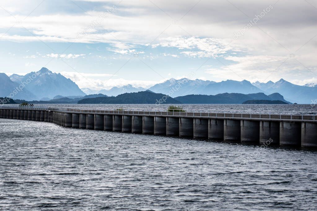 Pedestrian bridge that crosses the lake, surrounded by imposing mountains. Bariloche, Argentina