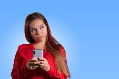 Genç bir kadın mesaj yolluyor. Şüpheli yüzlü bir kadın telefonuyla mesaj yolluyor. akıllı telefon.