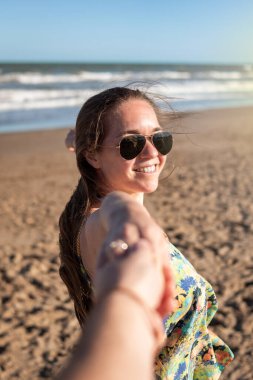 Seçici odaklanma. Kumsaldaki genç kadın. Yakın plan kadın plaja gitmek için ortağının elini tutuyor. Yaşam tarzı. Kumsaldaki mutlu kadın. Yaz günü