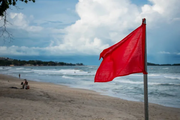 Red flag in the sea, a sign that swimming is prohibited. Sea with many waves, red flag that alerts tourists.