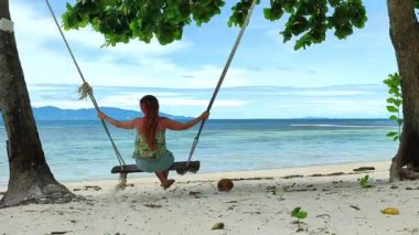 Kumsalda hamak kullanan genç bir kadın. Kumsalda eğlenen kadın. Tayland sahillerinde tatilde olan bir kadın.