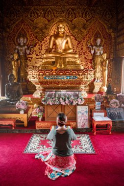 Budist tapınağında dua eden genç bir kadın. Tayland 'da tapınakta dua eden bir kadın. Diz çöküp dua eden kadın