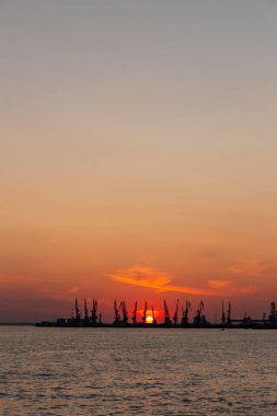 Berdyansk limanının arka planına karşı Azov Denizi 'nin turuncu yaz günbatımı.