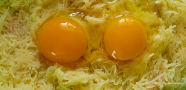 Kırık tavuk yumurtası ve rendelenmiş patates. Yemek, patates gözlemesi, yemek.