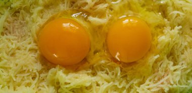 Kırık tavuk yumurtası ve rendelenmiş patates. Yemek, patates gözlemesi, yemek.