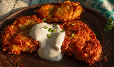 Fried potato pancakes on a clay brown plate, sour cream, green onions. food, potato pancakes, dish