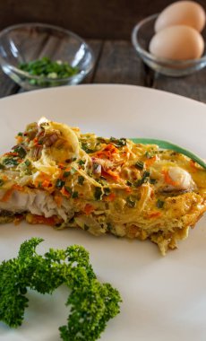 Balık, yumurta, soğan ve havuçtan yapılmış bir parça turta. Beyaz tabaklar, tahta tahtalar.