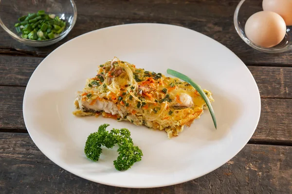 Balık, yumurta, soğan ve havuçtan yapılmış bir parça turta. Beyaz tabaklar, tahta tahtalar.