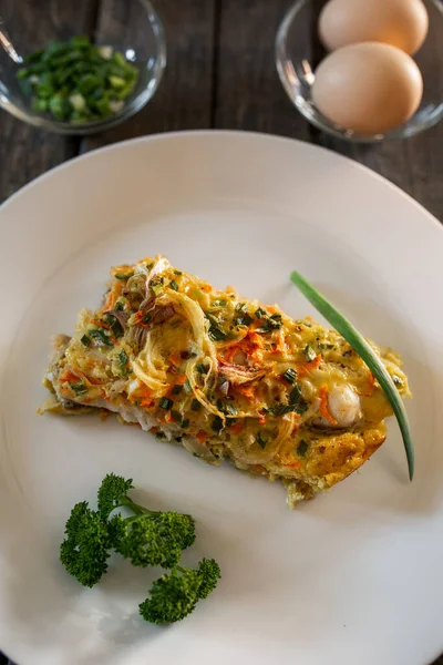 Balık, yumurta, soğan ve havuçtan yapılmış bir parça turta. Beyaz tabaklar, tahta tahtalar.