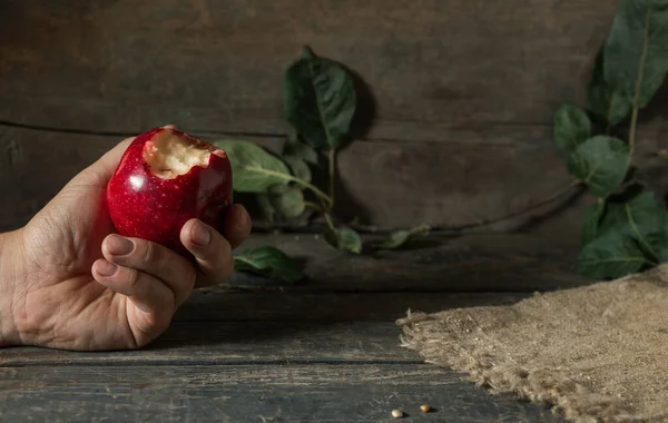 Mão Uma Maçã Vermelha Mordida Com Folhas Serapilheira Tábuas Madeira — Fotografia de Stock