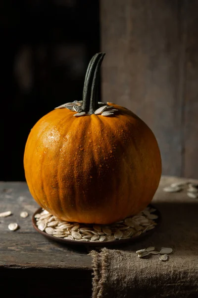 Pumpa Droppar Vatten Tallrik Med Pumpafrön Ett Träbord — Stockfoto