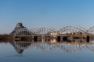Letonya 'nın Riga kentindeki Daugava Nehri üzerindeki demiryolu köprüsü baharda aydınlık bir gün.