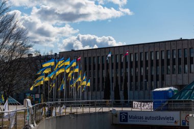 Riga, Letonya. 31 Mart 2022. Ukrayna 'daki savaşı protesto etmek için Rusya Büyükelçiliği' nin yanındaki Riga Kongre Merkezi önünde sallanan bir grup Ukrayna bayrağı