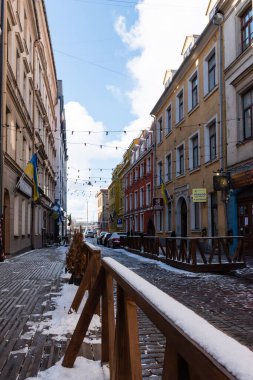 Riga, Letonya. 30 Mart 2022. Old Town 'da biraz karlı renkli binaların olduğu bir cadde.