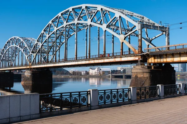 Riga, Letonya 'daki Daugava Nehri üzerindeki demiryolu köprüsü baharda güneşli bir gün.