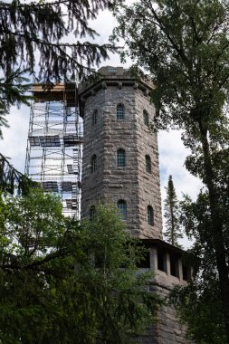 Hameenlinna, Finland. July 24, 2022. The Aulanko observation tower being under renovation seen from between the trees in summer, Hmeenlinna, Finland