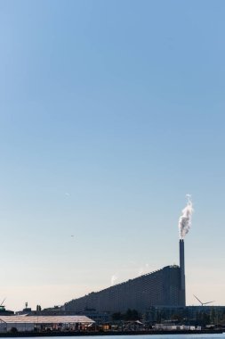 Copenhagen, Denmark. August 13, 2022. Amager Bakke, a combined power plant and ski slope seen from the other side of the river against a blue sky.