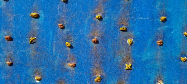 blue rock climbing wall with rustic texture and orange support points