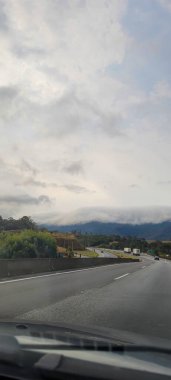 Minas gerais 'nin güney manzarası yolda hareket eden araba, dağlarla kaplı bulutlu.