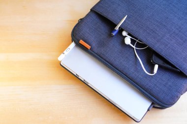 İçinde stilus kalem, cep telefonu, kulaklık ve laptop olan mavi dizüstü bilgisayar çantası.