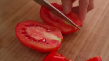 Mutfakta domates kesen bir kadın.