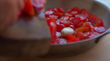 Tavaya dilimlenmiş vişneli domates koyan kadın.