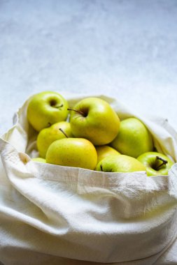 Beyaz arka planda yeşil elmalarla dolu bir çevre çantası