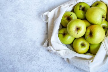 Beyaz arka planda yeşil elmalarla dolu bir çevre çantası