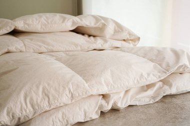 Yatak odasında katmanlı beyaz yorgan. 