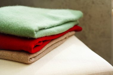 Beyaz sandalyede yün örülü süveterler