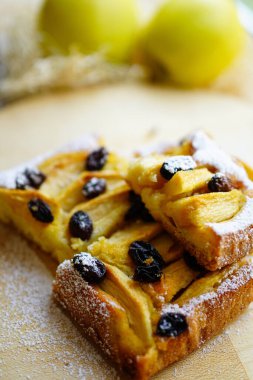 Ev yapımı elma keki, üzerine toz şeker serpiştirilmiş üzümler serpiştirilmiş.