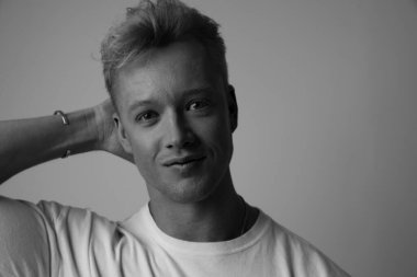 Beyaz arka plana gülümseyen yakışıklı bir adamın siyah beyaz portresi..