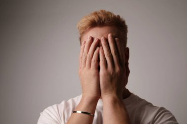 Elleri suratında oturan yakışıklı bir gencin vesikalığı. Stres, sorunlar.