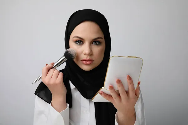 Jovem mulher arabe bonita vestindo hijab islâmico fazendo sua maquiagem. Interior. — Fotografia de Stock