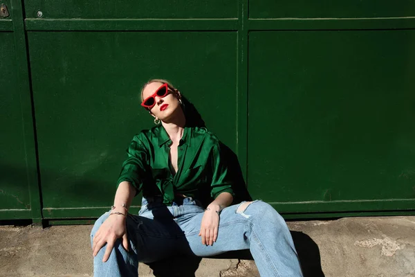 Nahaufnahme einer jungen blonden, stylischen Frau, die Sonnenbrille trägt und im Freien posiert. — Stockfoto