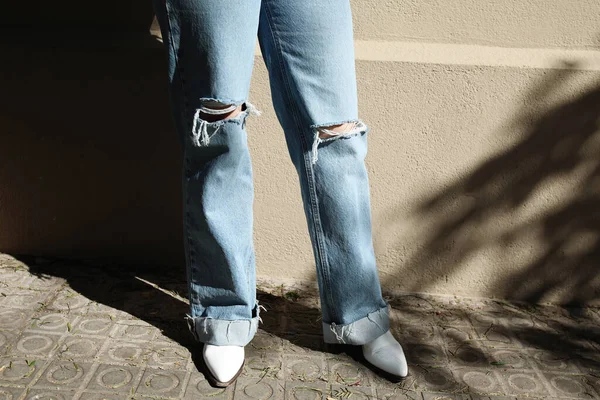 Photo recadrée de femme courbée posant en jean bleu et bottes de cow-boy blanc. — Photo