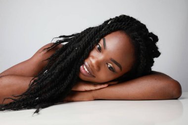 Kendine güvenen, örgülü genç bir kadının yakın portresi. Beyaz duvarda izole edilmiş..