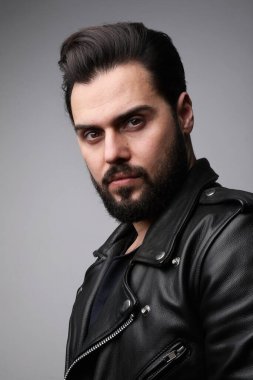 Deri ceket giyen sakallı bir gencin dikey portresi. İzole edilmiş.