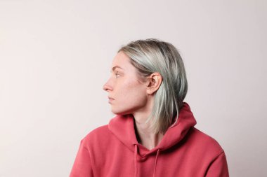 Stüdyoda poz veren renkli saçlı mutlu genç bir kadının yan portresi..