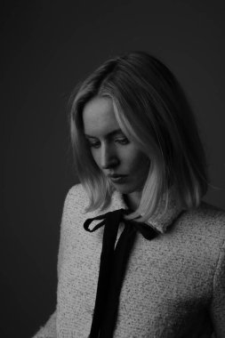 Siyah arka planda poz veren genç bir kadının dikey siyah beyaz portresi.