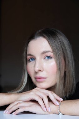 Siyah arka planda poz veren hoş beyaz bir kadın. Dikey çekim.