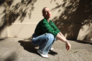 Young and fashionable blonde hipster woman, with closed eyes, posing outdoor.